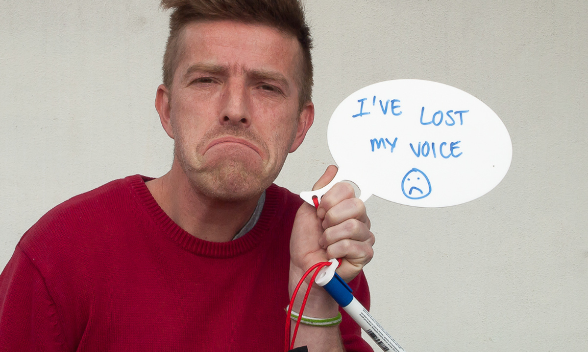 Lost Voice Whiteboard - A friend poses with a sad face and holds the whiteboard speech bubble with the message 'I've lost my voice'