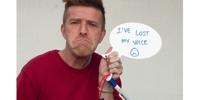 Lost Voice Whiteboard - A friend poses with a sad face and holds the whiteboard speech bubble with the message 'I've lost my voice'